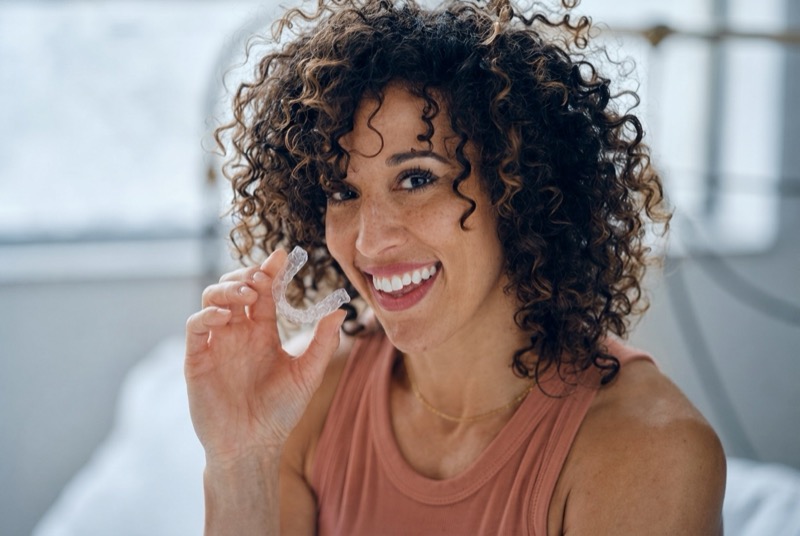Patiente souriante tenant sa gouttière orthodontique transparente